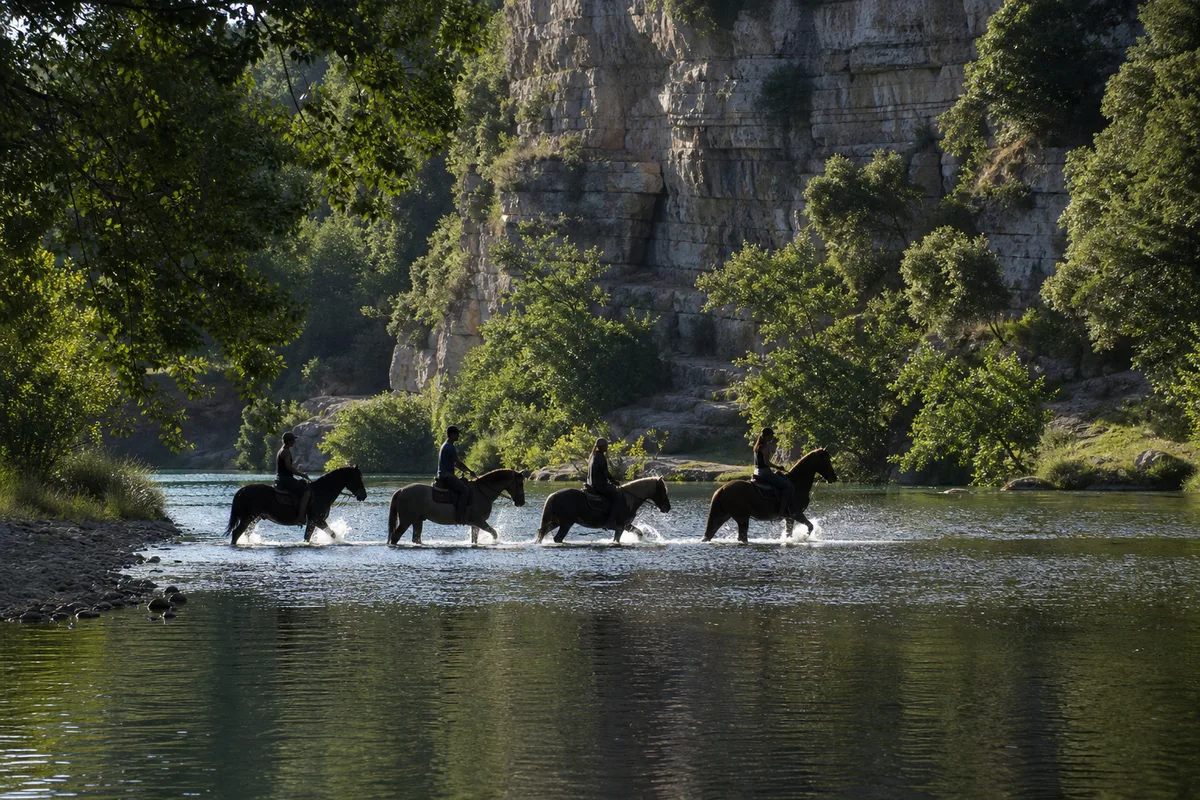 Famille à cheval au bord d&rsquo;une rivière bordée d&rsquo;arbres en été